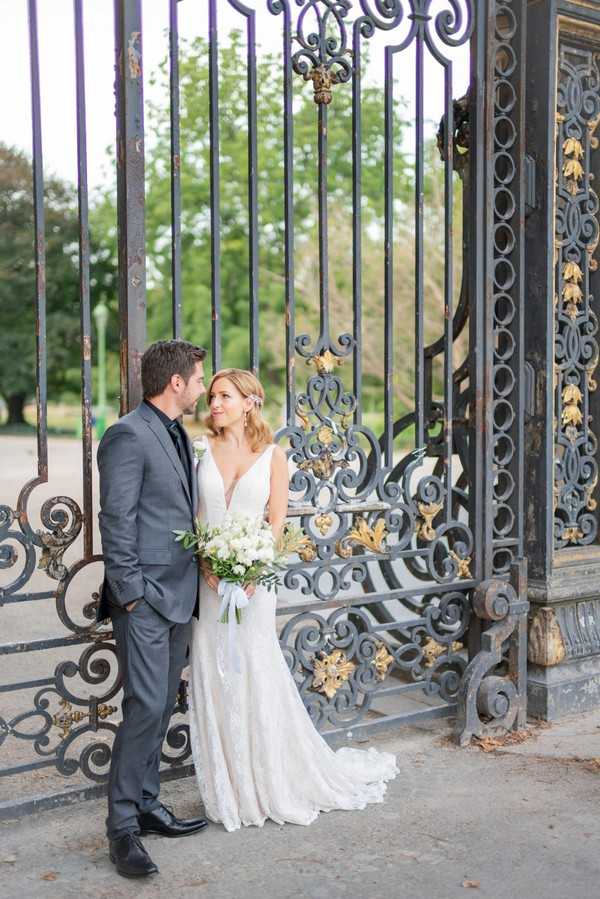 bride and groom look at each other in front of wrought iron gates