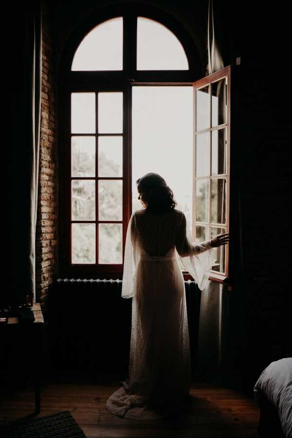 Silhouette of bride in arched window Chateau de Fajac for modern cultural affair