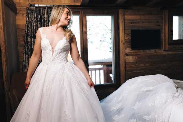 bride looks over her shoulder and smiles, her wedding dress trails behind her