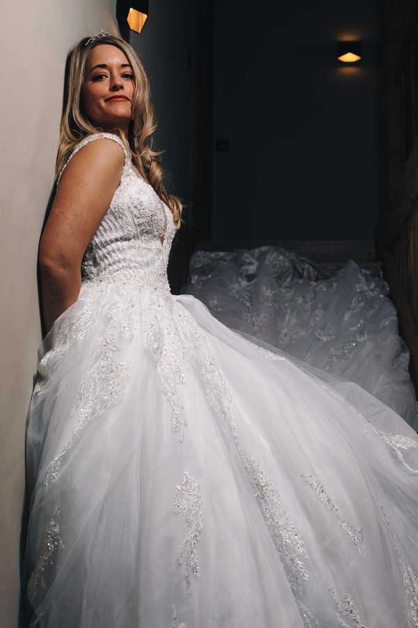 bride leans against wall and smiles down to camera standing in a stairwell