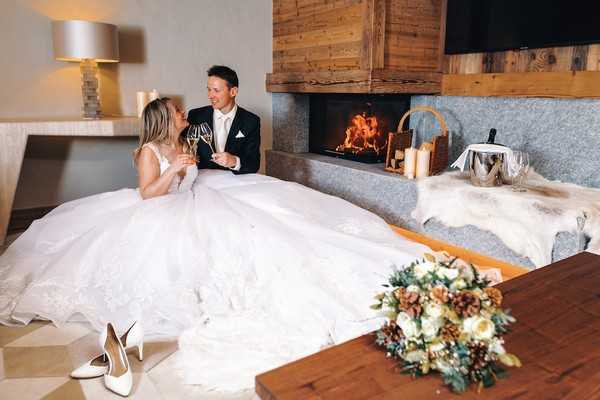 bride and groom cheers champagne in front of a fire in a private chalet in Saint-Nicolas de Véroce