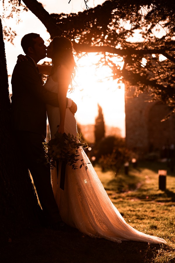 Silhouette of bride and groom kissing in the sunset