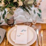 Wedding table place setting with bare wooden table and botanicals