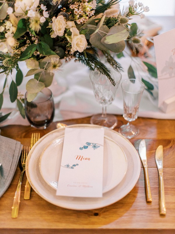 Wedding table place setting with bare wooden table and botanicals