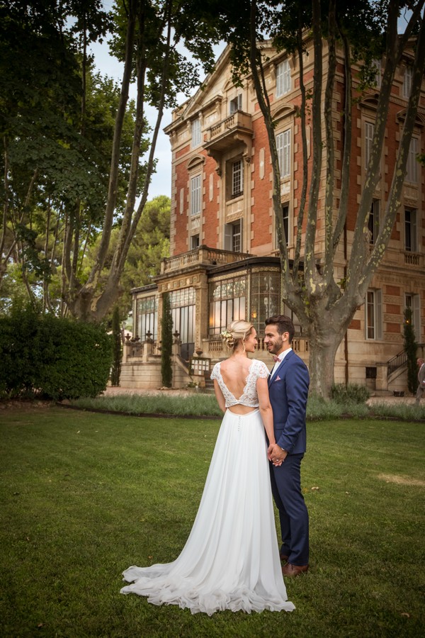 Couple stand on the grass outside a French Chateau after their wedding