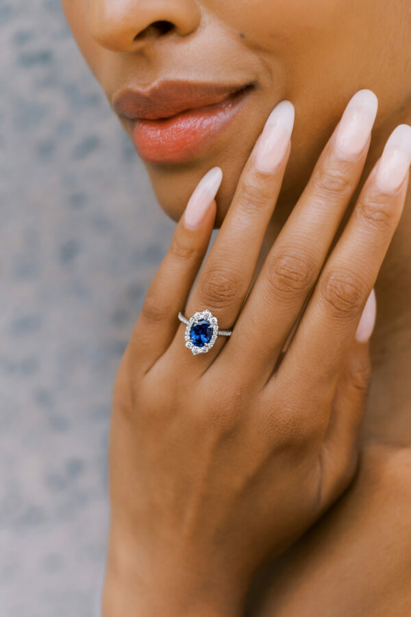 Large blue sapphire and diamond ring on engagement finger of lady