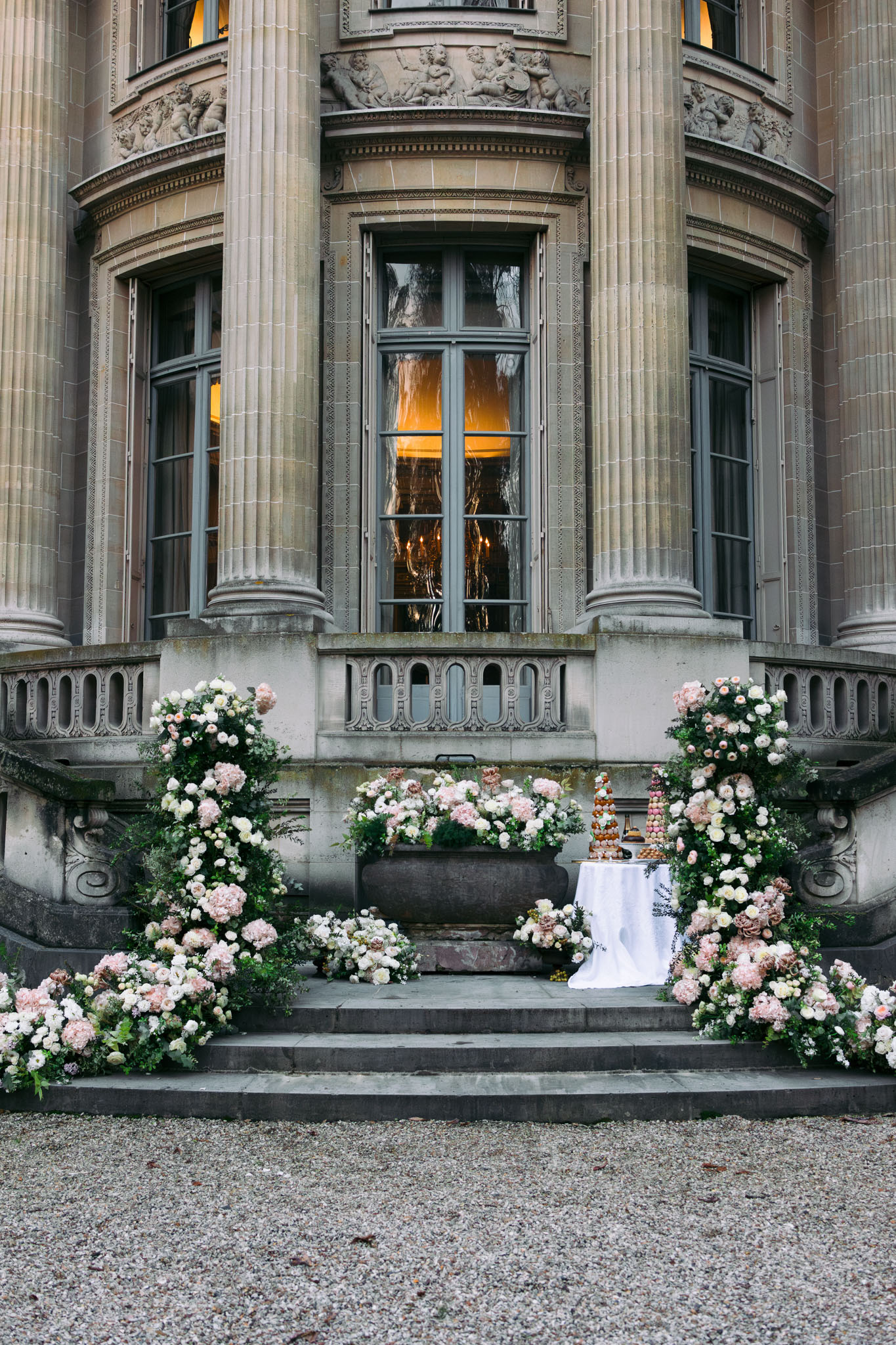 Croquembouche and macaron tower flanked by cascading blush hydrangea installations on chateau steps at dusk