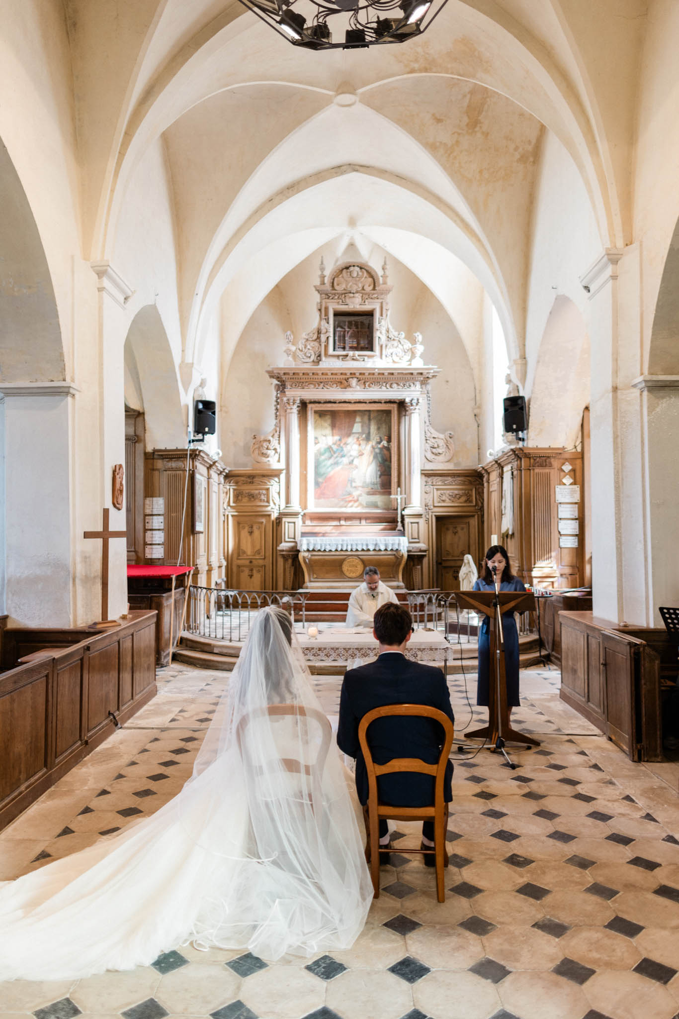 Wedding ceremony inside Gothic chapel with ribbed vaulting and baroque altarpiece viewed from nave
