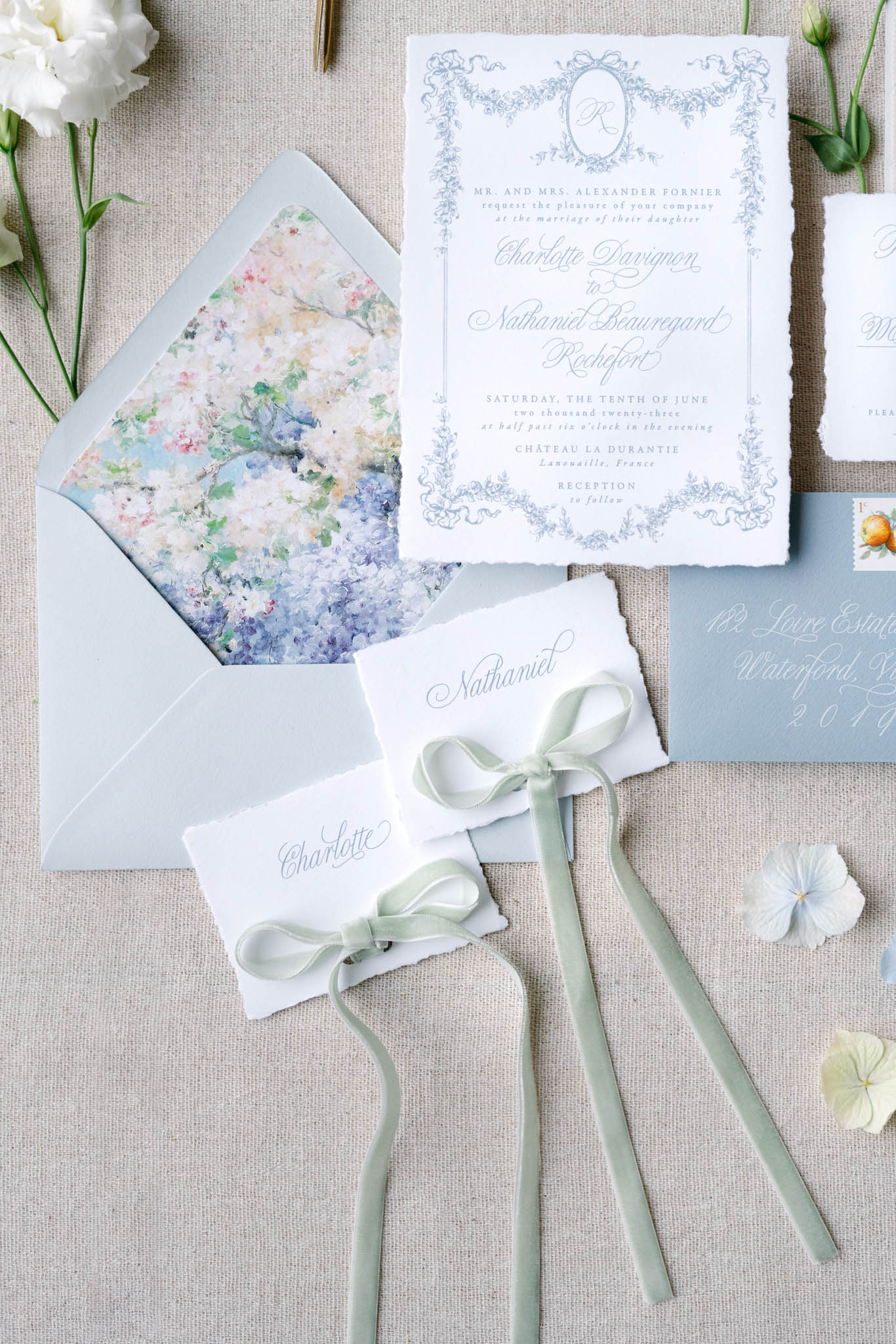 Dusty blue invitation suite with sage ribbon place cards and watercolor floral envelope liner