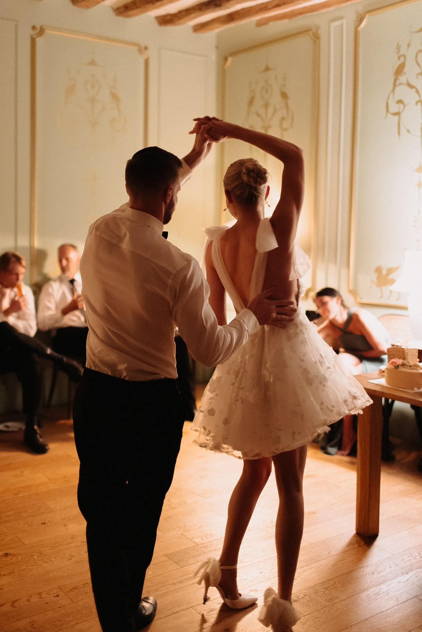 Couple sharing first dance in chateau room with ornate gold paneling and wooden beams