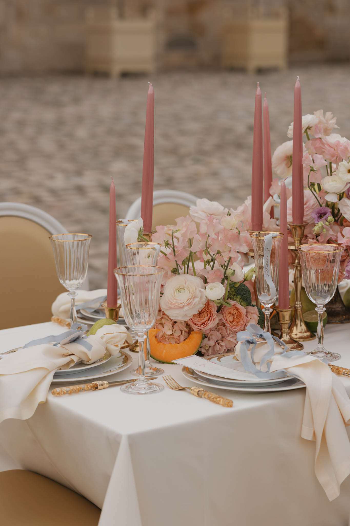 Tablescape with blush roses, cantaloupe, dusty rose candles, gold cutlery, and calligraphy menu cards