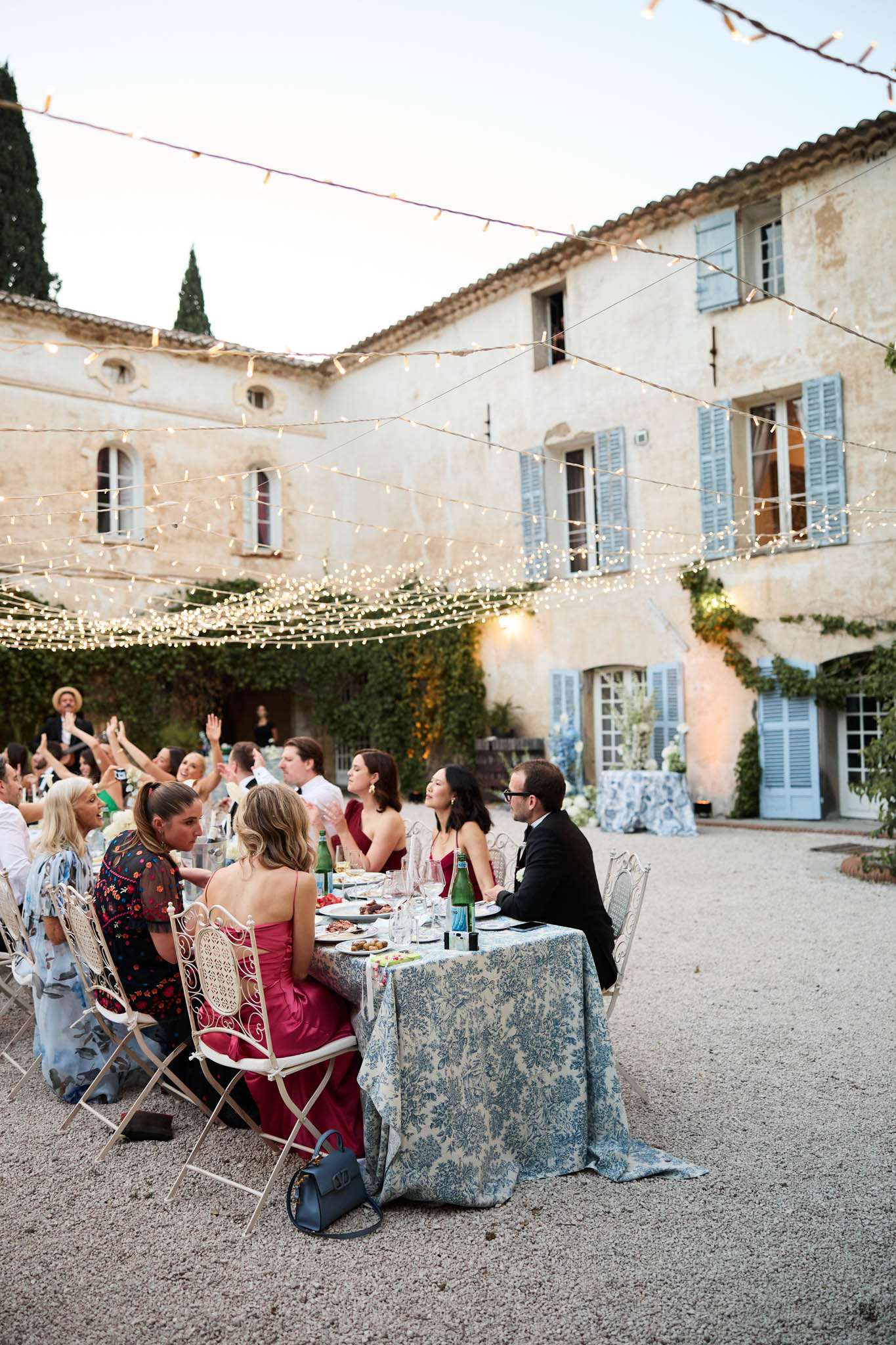 Fairy-lit courtyard dinner with blue toile tablecloths and white bistro chairs at Provencal bastide