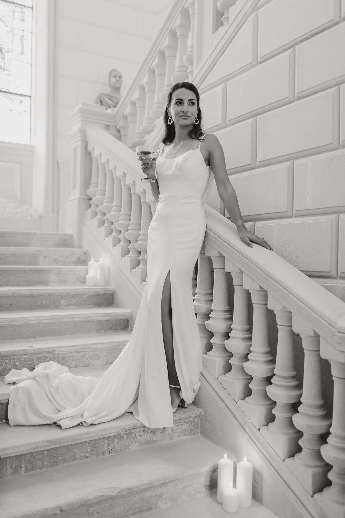 Black-and-white bridal portrait on a grand stone staircase with classical balusters and candles