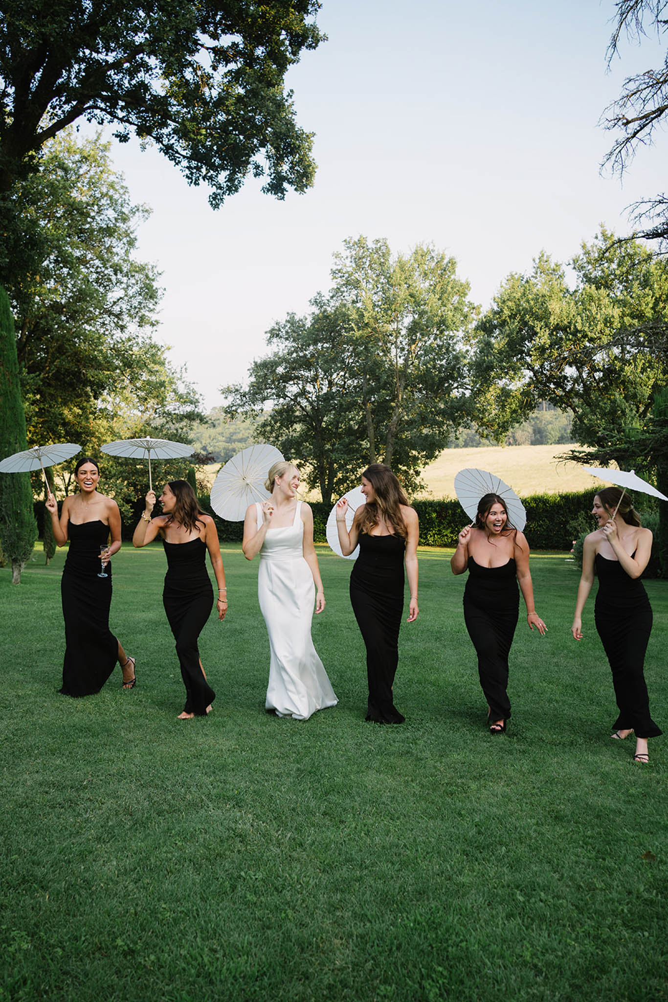 Outdoor ceremony at ChÃ¢teau de Fontareches with floral arch and guests seated in garden