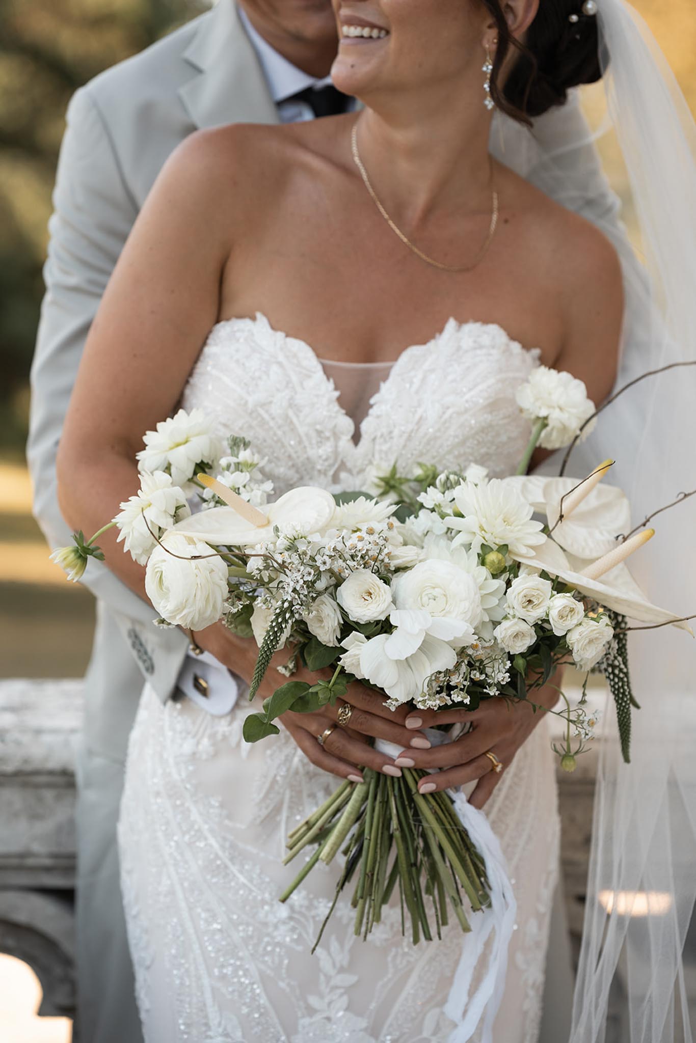 Bride and groom posing beside a vintage car at their wedding