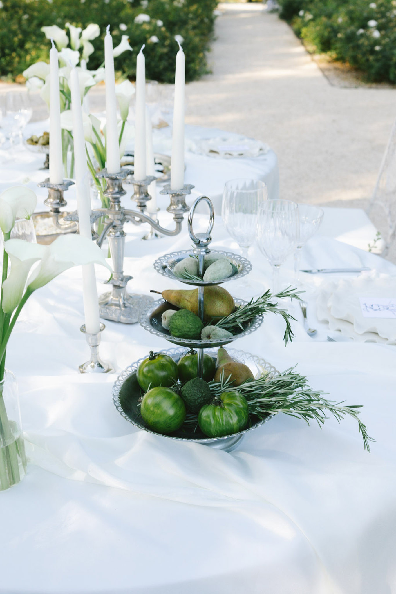 Outdoor reception table with silver three-tiered fruit stands, calla lily arrangements and silver candelabras