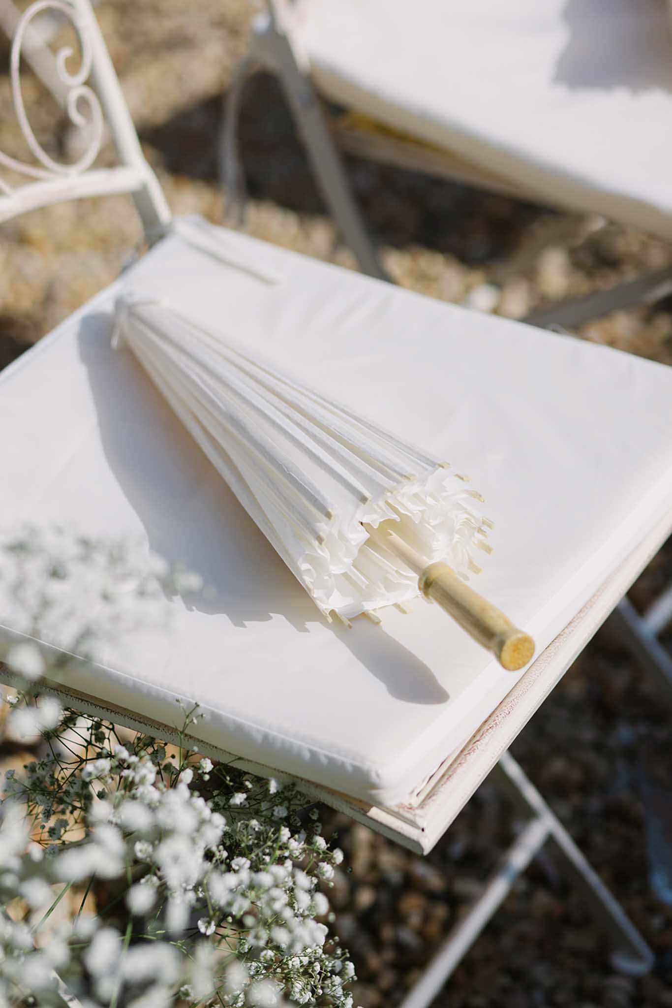 Outdoor ceremony setup at ChÃ¢teau de Fontareches with white umbrellas and white chairs in garden