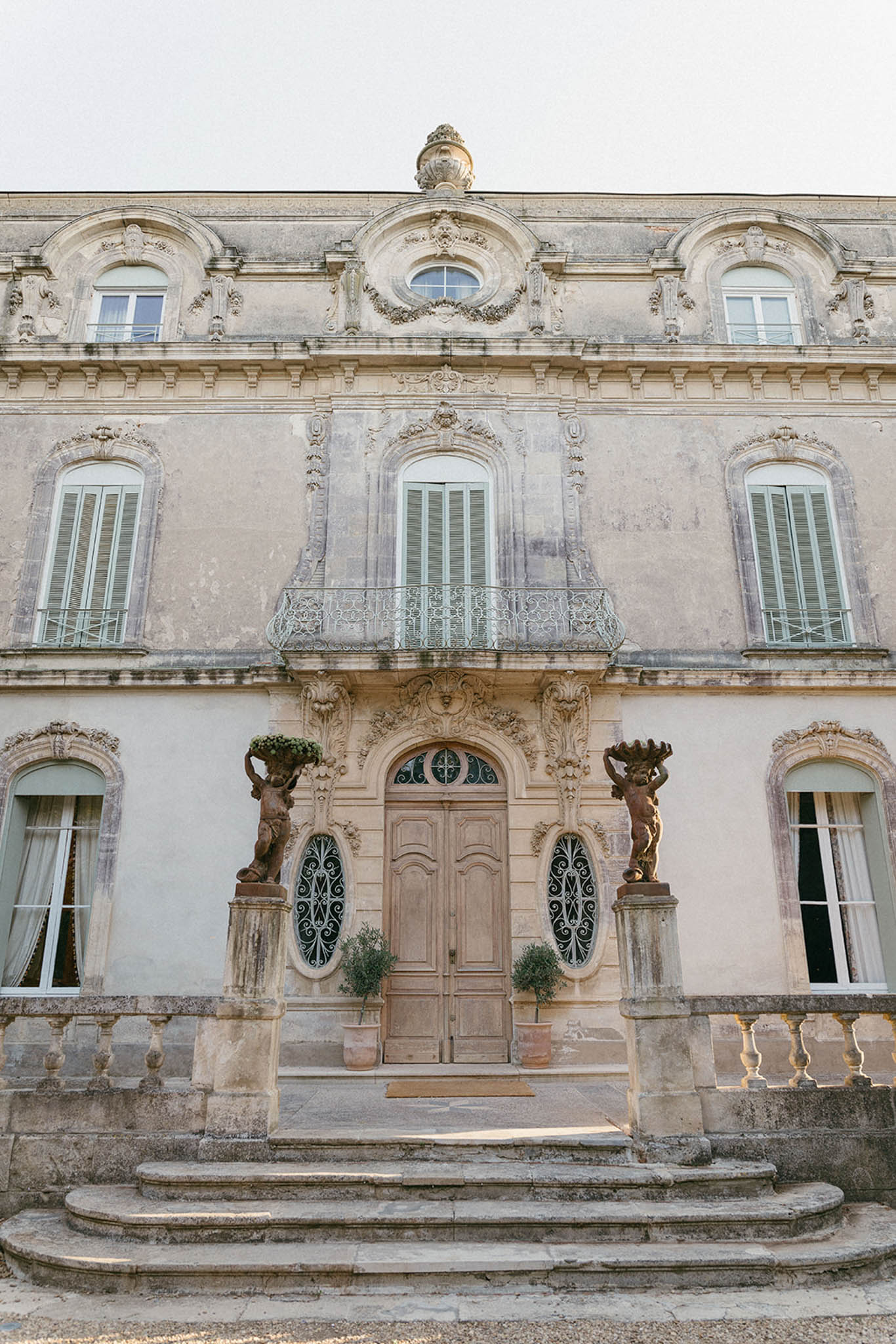 Symmetrical facade of Haussmann-style limestone mansion with bronze caryatid figures and wrought-iron balcony