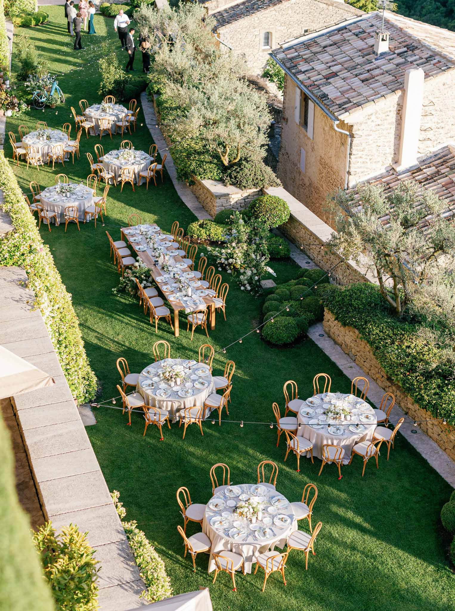 Aerial view of round reception tables on lawn beside Tuscan stone villa