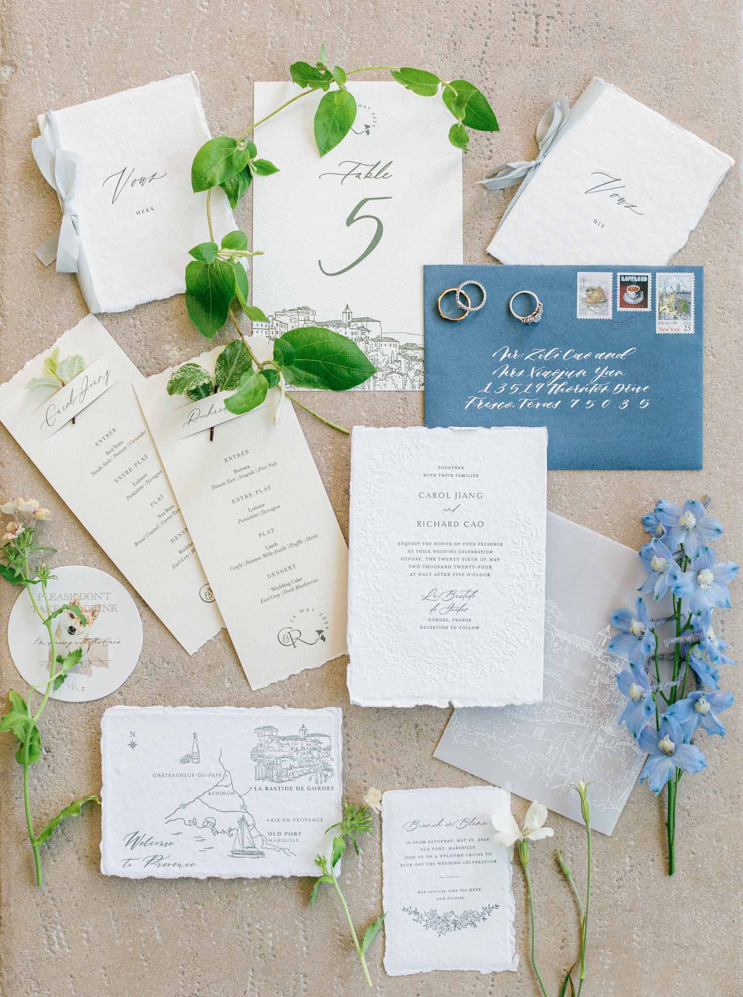 Flat lay of wedding invitation suite with blue decor and green accents at Bastide de Gordes by Despinoy