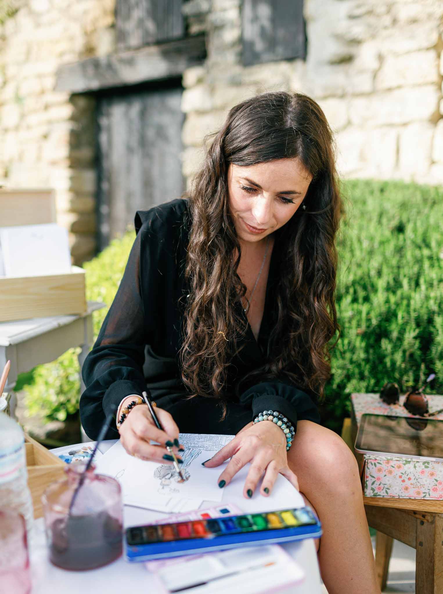 Painter seated at corner table creating a live painting at Bastide de Gordes during wedding reception