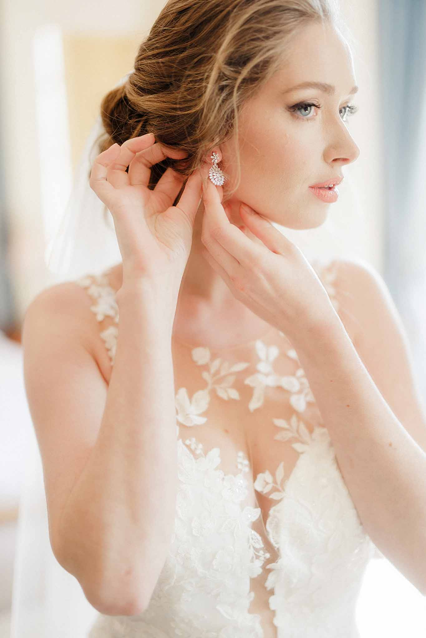 Bride putting on earrings while getting ready at ChÃ¢teau de Trieux