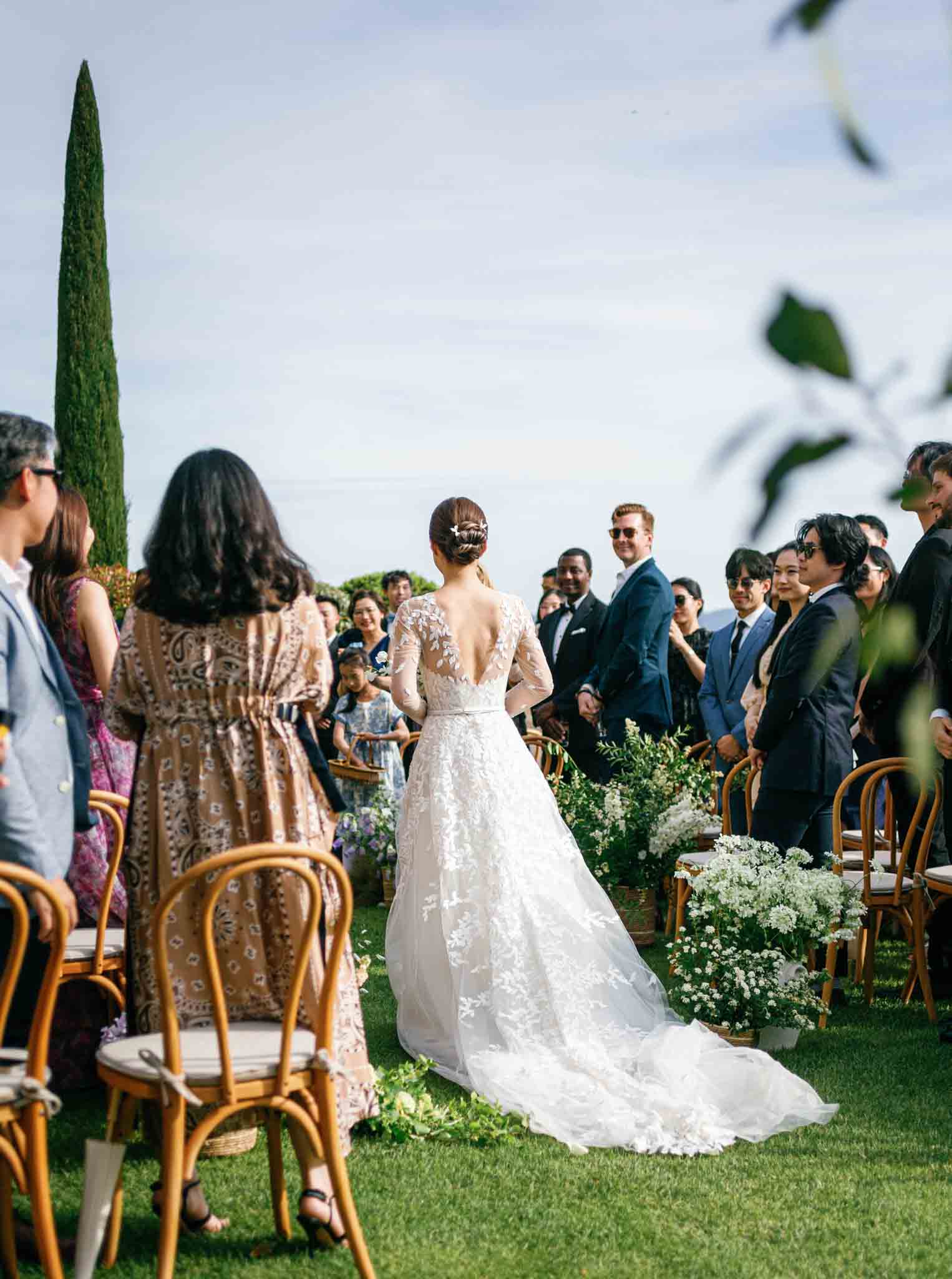 Outdoor garden ceremony with bride at altar, cypress trees, and baby's breath arrangements at Gordes