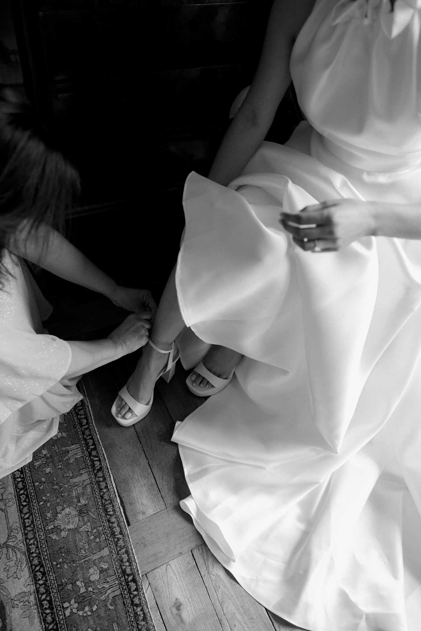 Bride putting on wedding shoes while getting ready at ChÃ¢teau de Bouthonvilliers, black and white