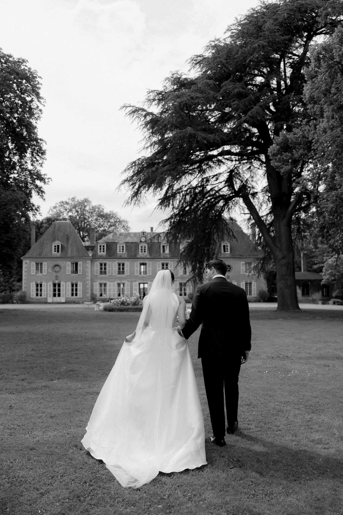 Bride and groom walking away from camera at ChÃ¢teau de Bouthonvilliers, black and white photograph