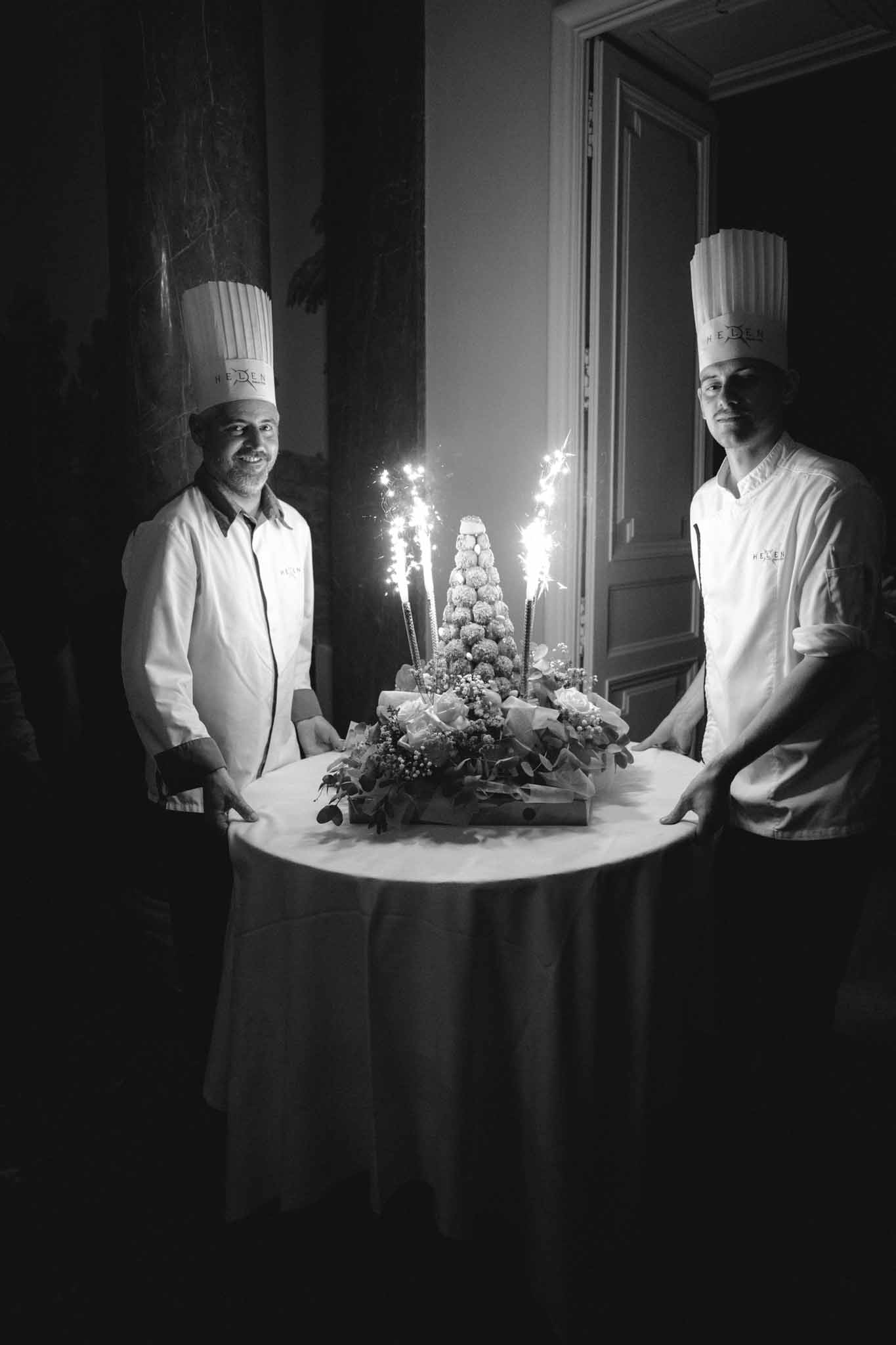 Black and white photo of croquembouche presentation with sparklers and two pastry chefs