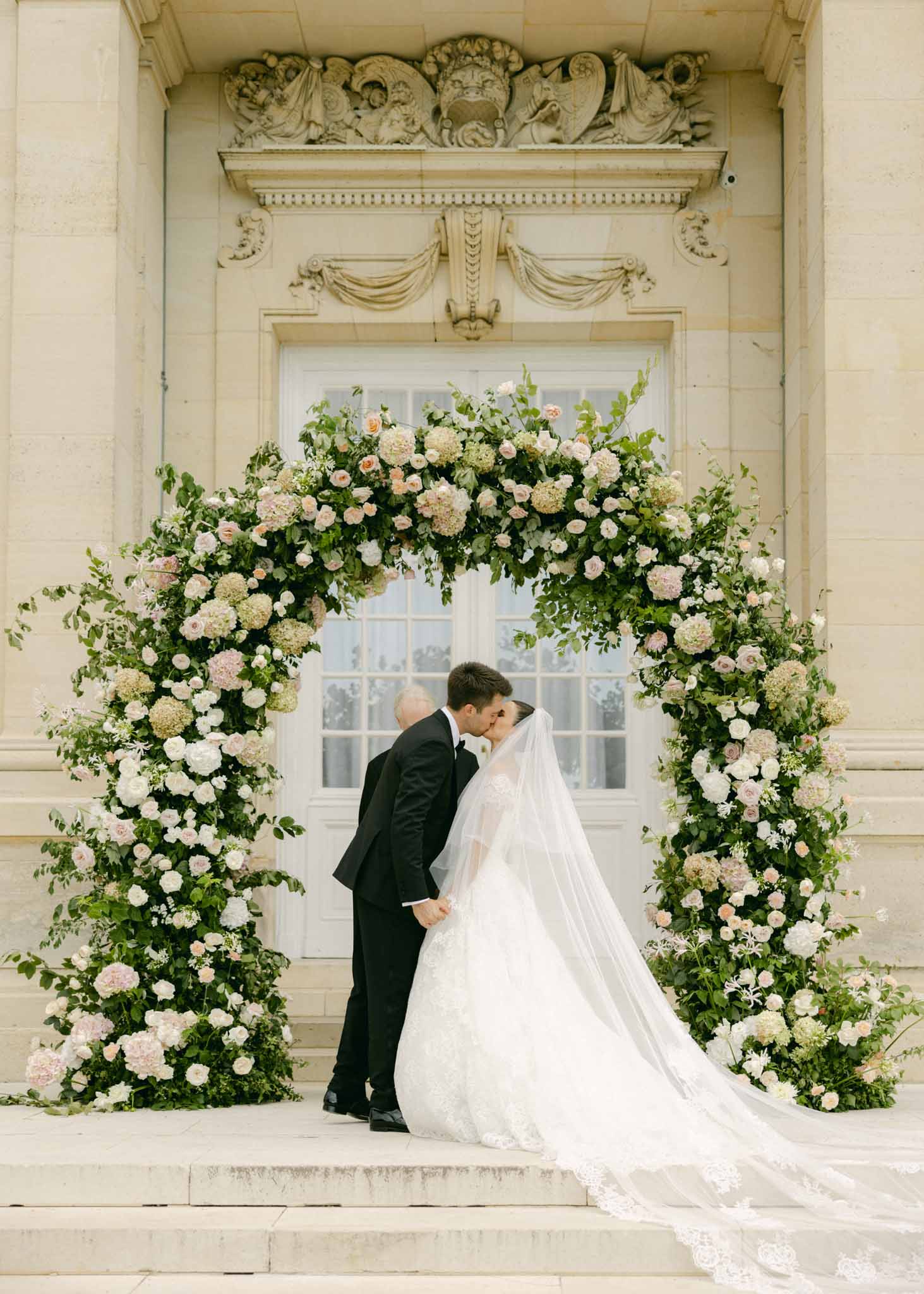 Bride and groom kiss during their wedding ceremony in a garden setting