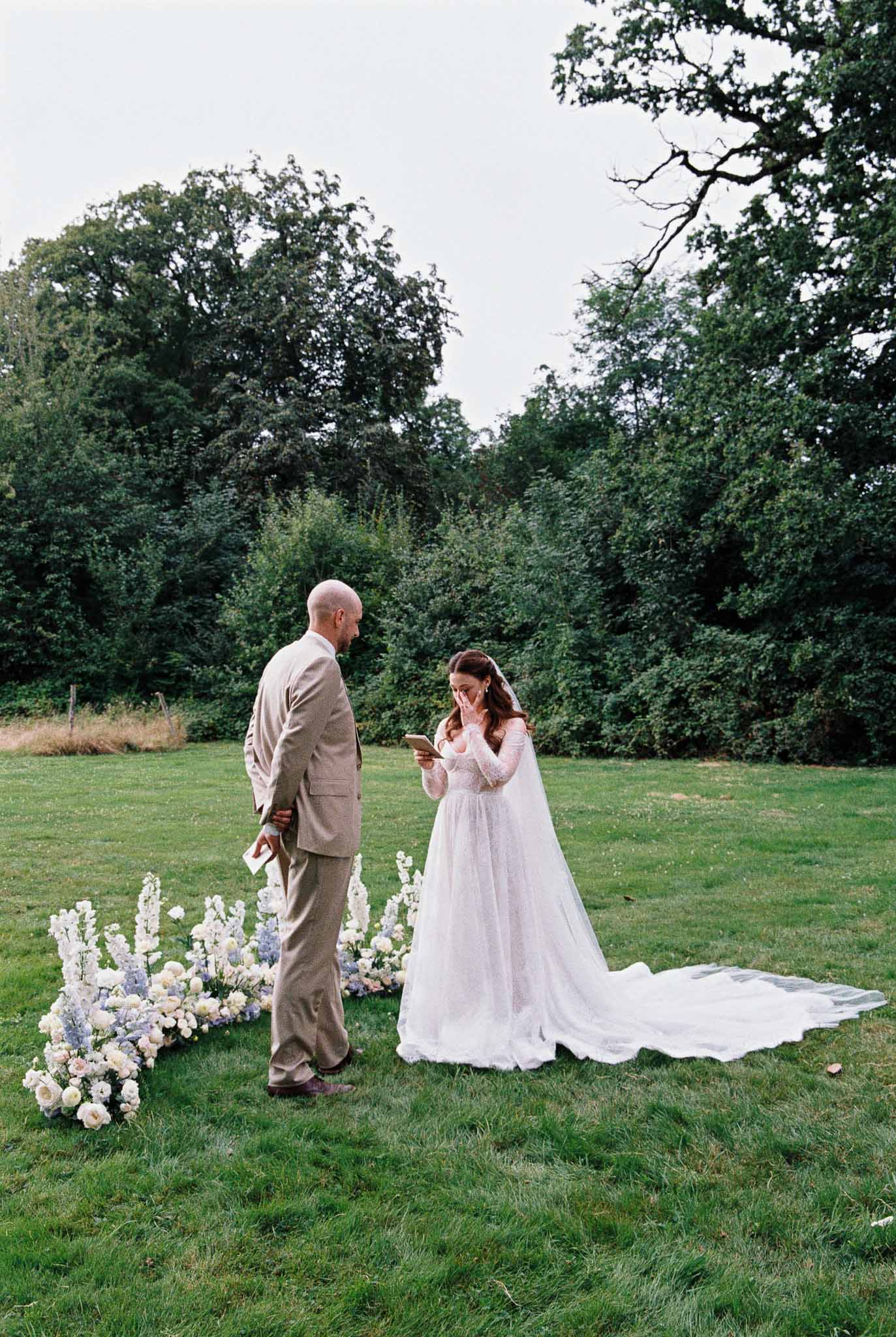 Bride and groom exchanging vows during outdoor garden ceremony with floral installation