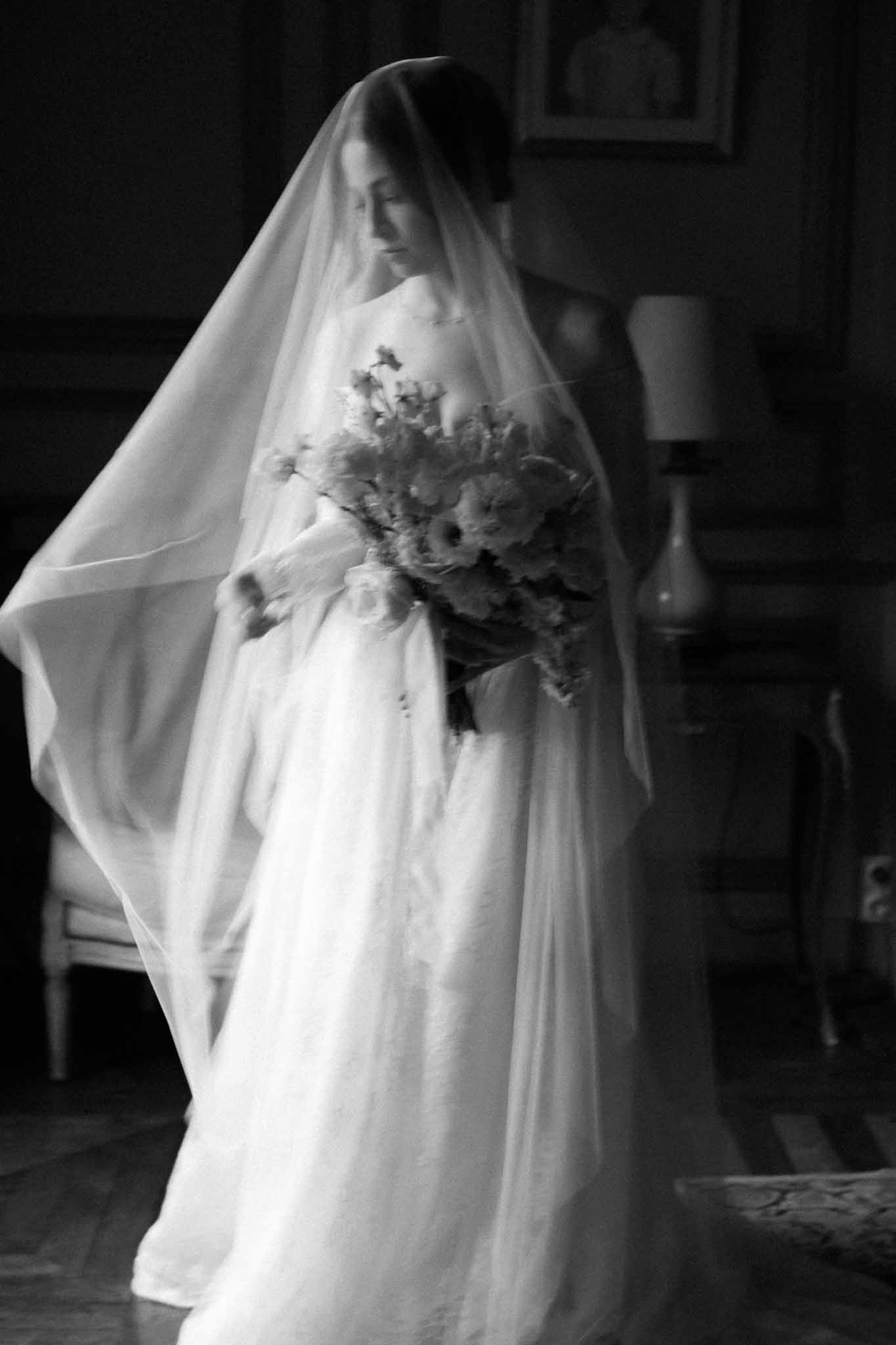 Black and white bridal portrait with veil and bouquet in indoor setting