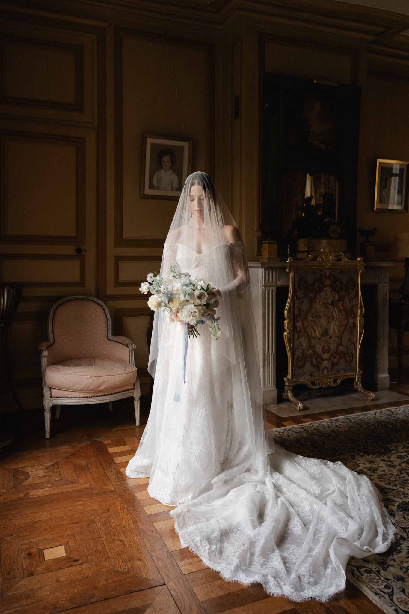 Bride in ivory lace gown with cathedral train posing in classical interior room with period details