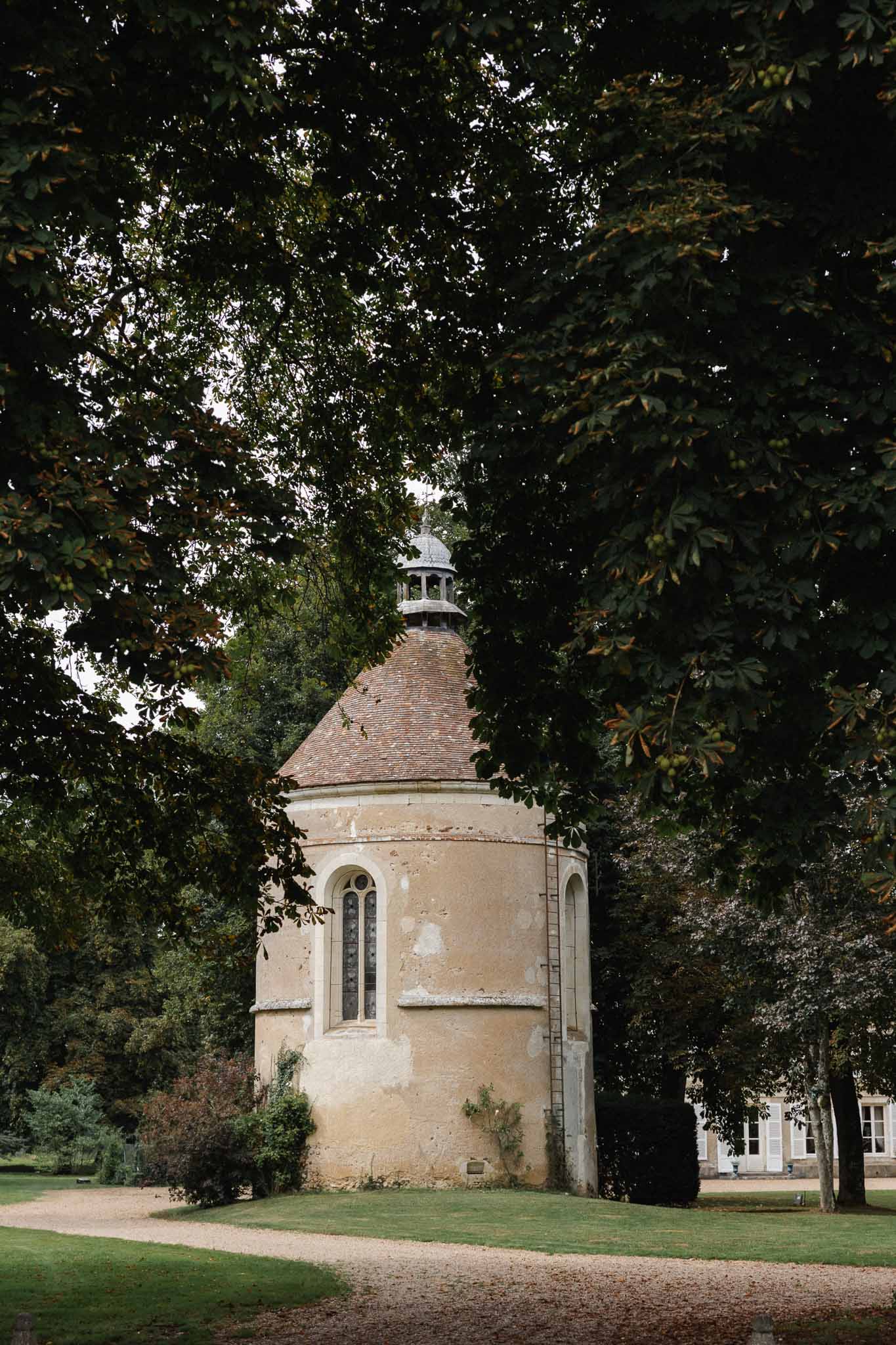 Historic stone chapel with cupola and terra cotta roof on manicured grounds