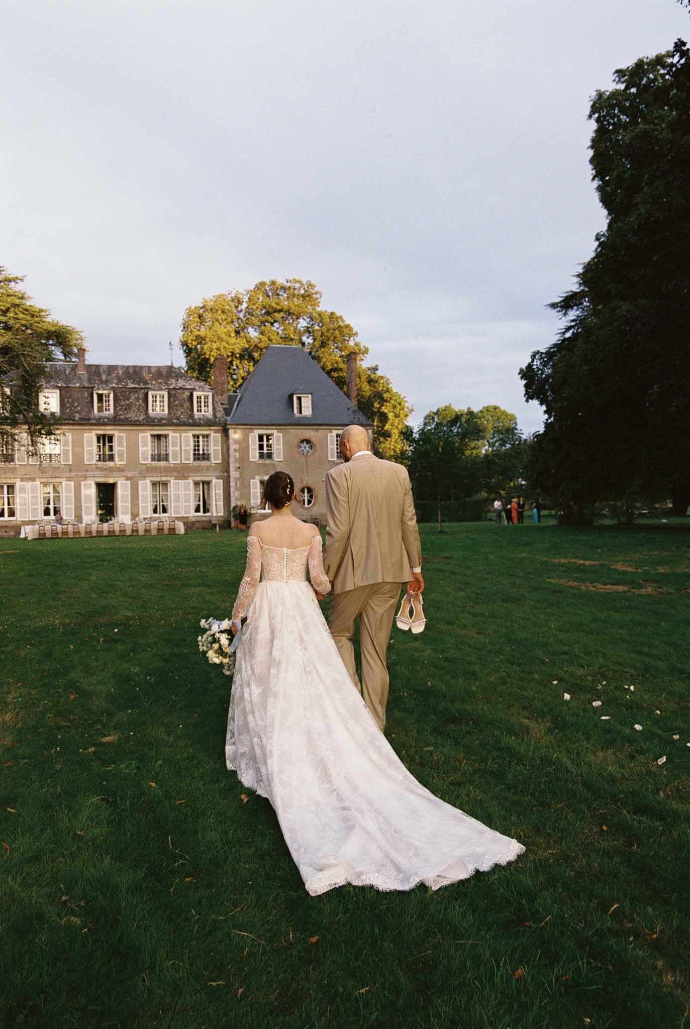 Bride and groom walking toward French chÃƒÂ¢teau during autumn wedding reception