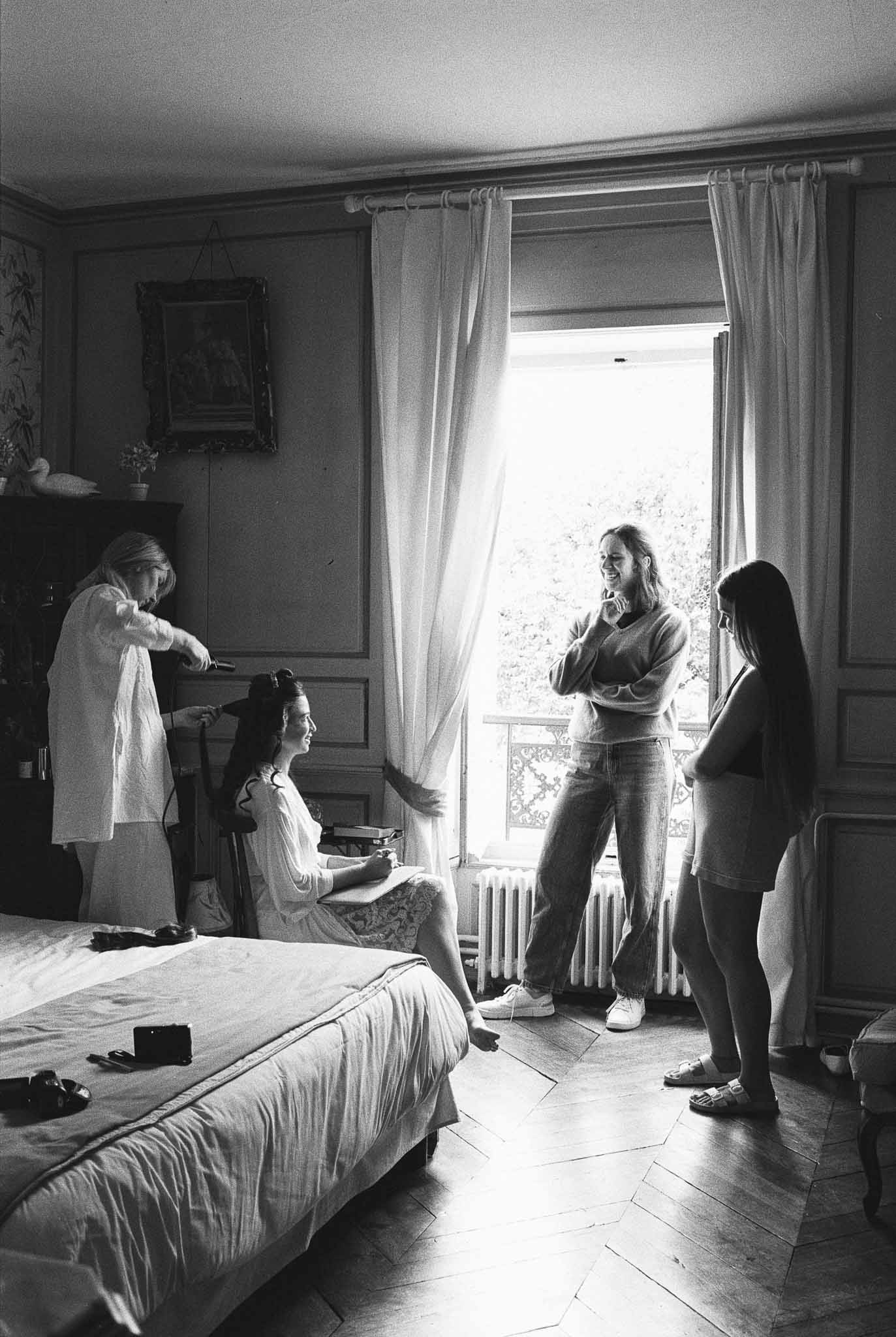 Bride getting ready with attendants adjusting veil in European manor bedroom