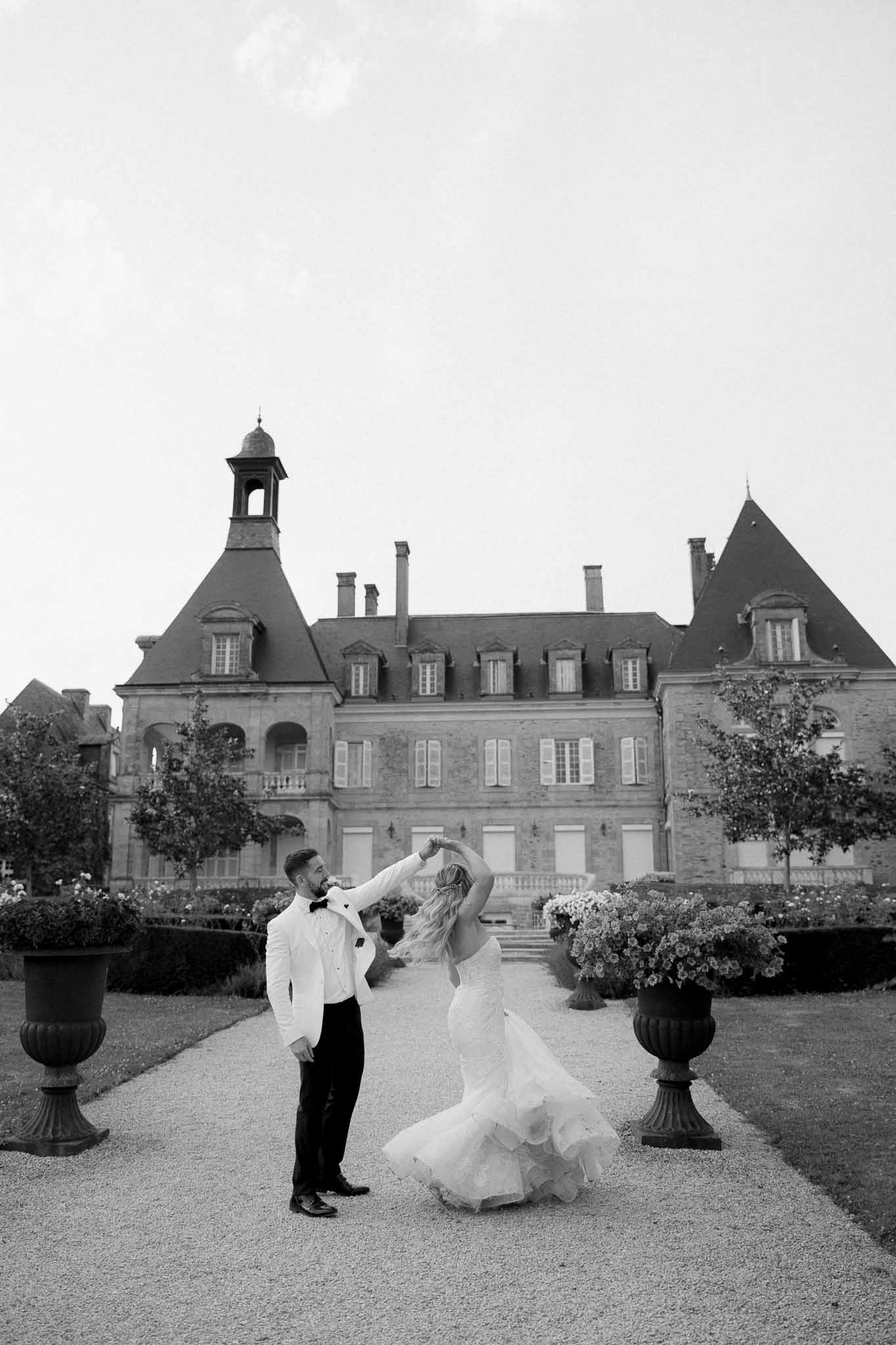 Bride and groom dancing in formal courtyard of French chÃƒÂ¢teau with stone architecture and manicured gardens