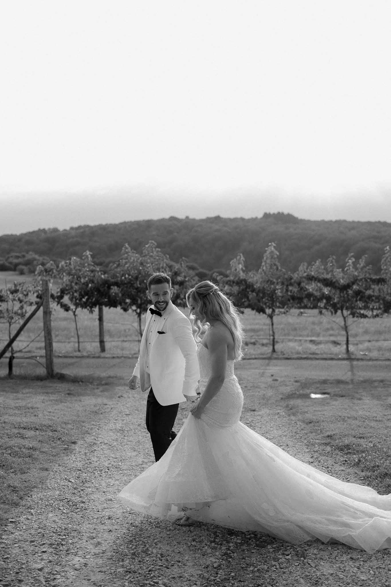 Bride and groom portrait on gravel road in vineyard with rolling hills background