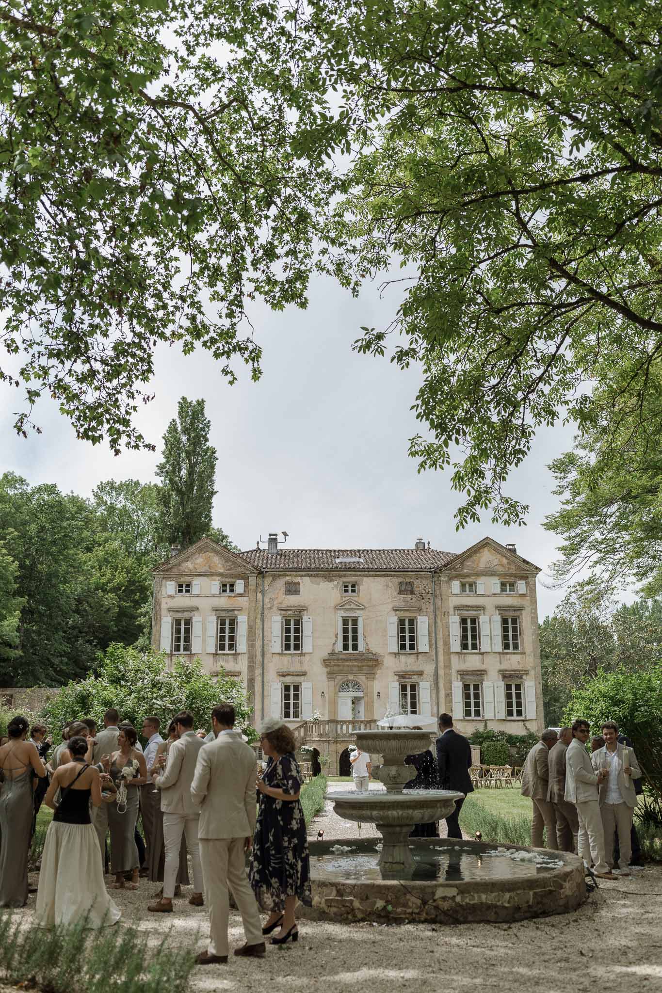 Cocktail hour with guests mingling in courtyard of classical stone manor house with fountain