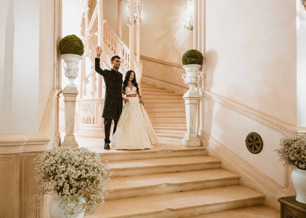 Chateau Challain F.Bandiera bride white dress lehenga groom black suit stairs reception