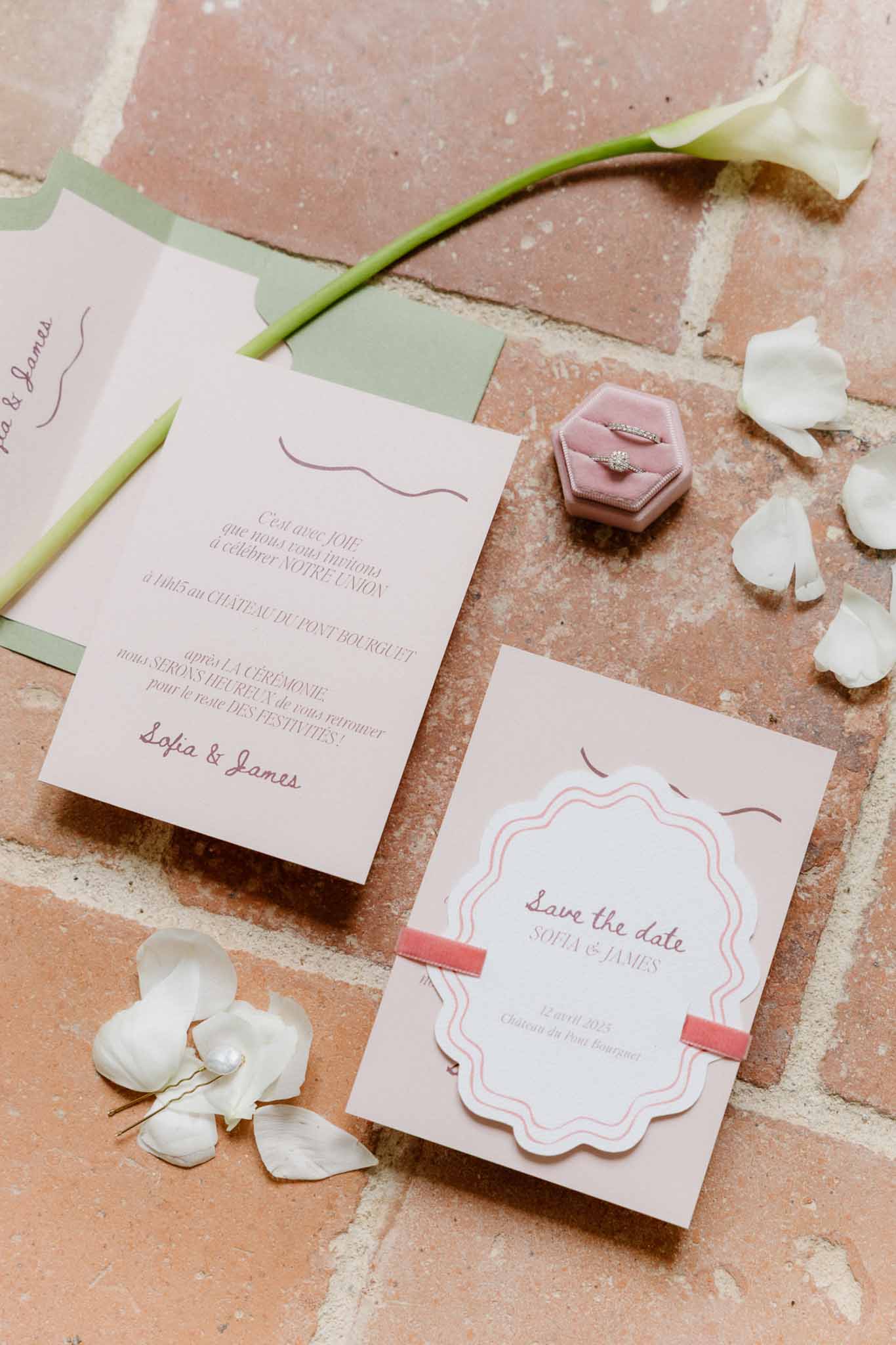 Wedding invitation suite with rings and calla lilies arranged on terracotta surface