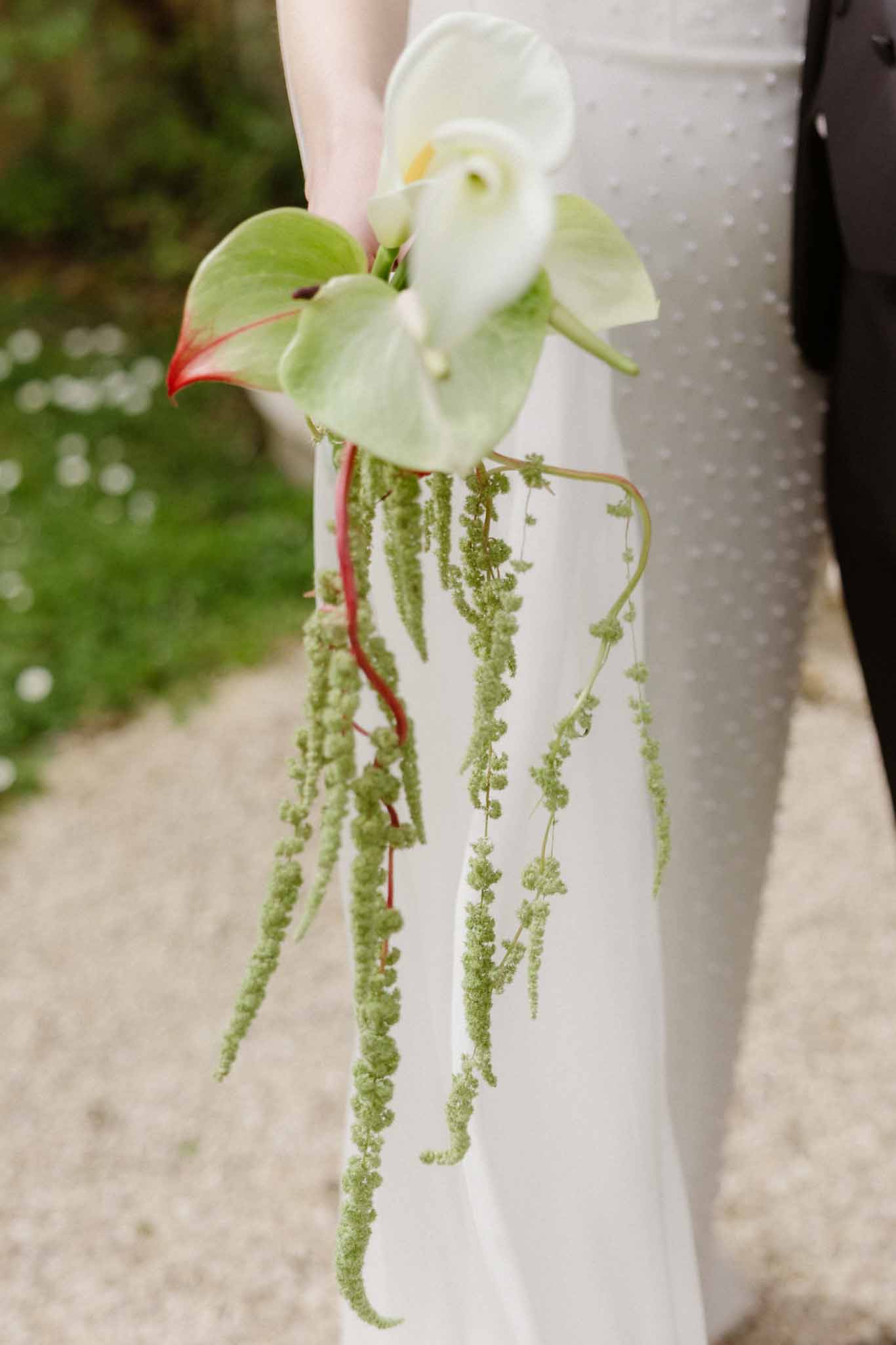 Bride holding calla lily bouquet with sage greenery in outdoor garden setting