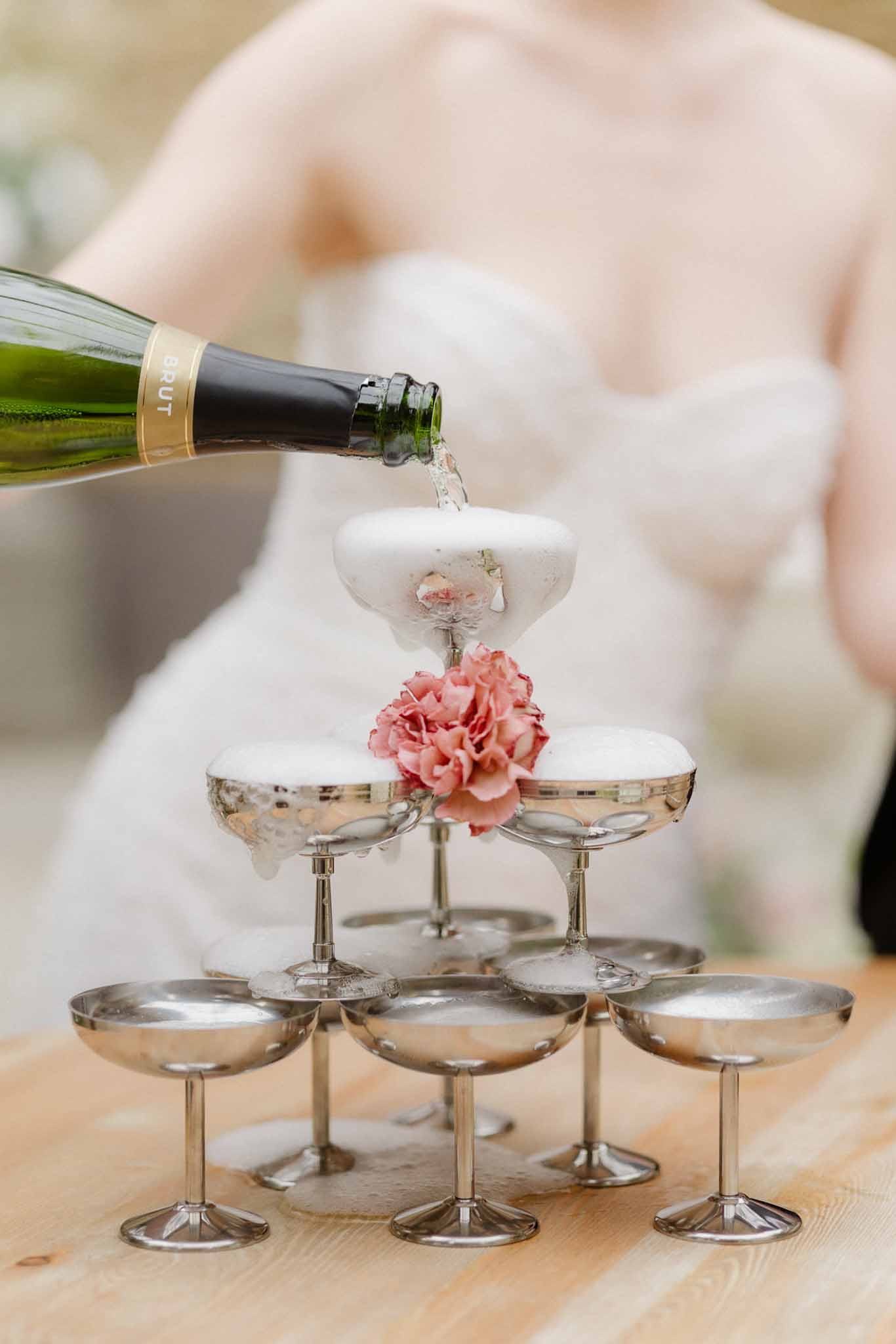 Champagne tower being filled with sparkling wine at wedding reception