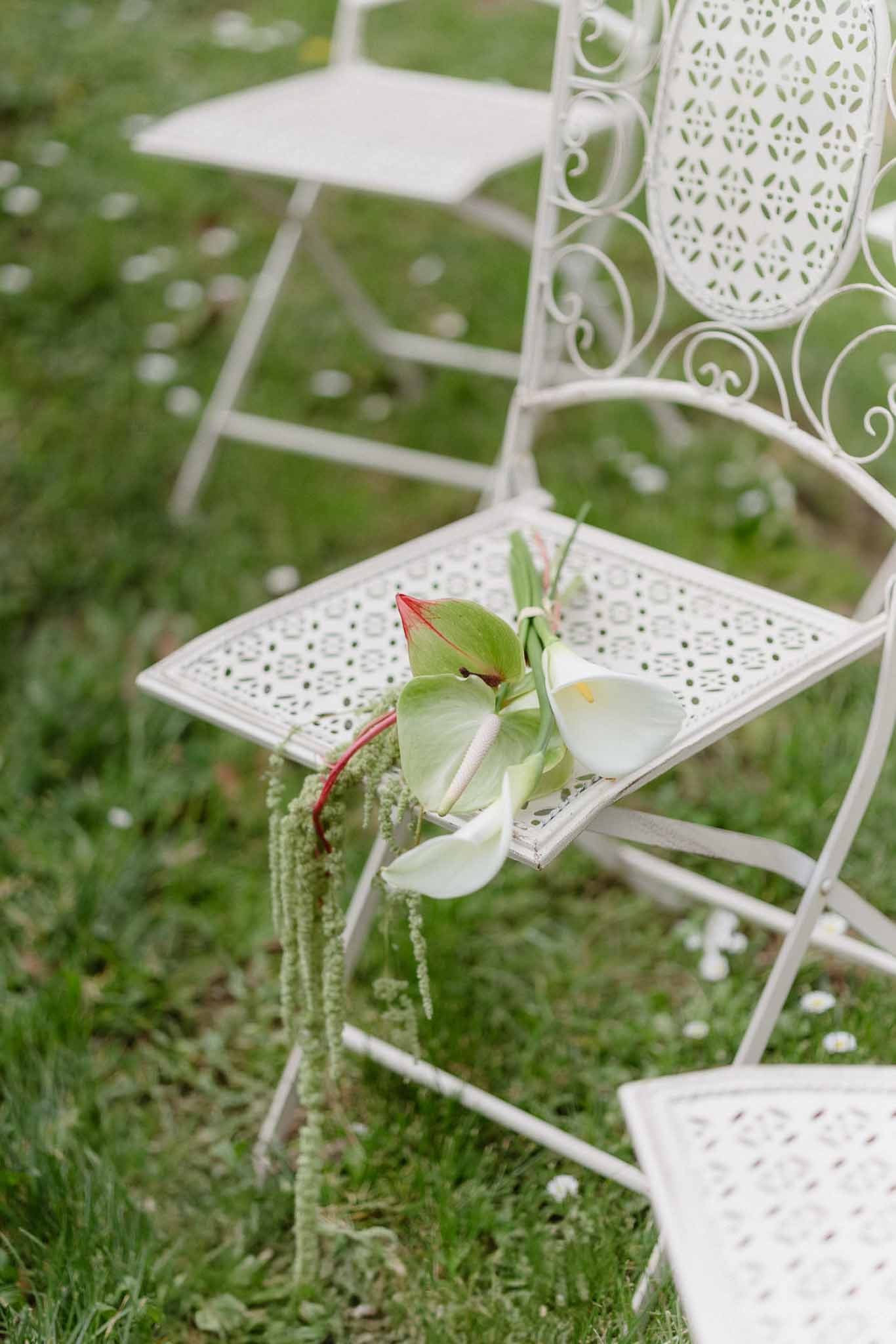 White metal ceremony chair with calla lily bouquet decoration at outdoor garden wedding