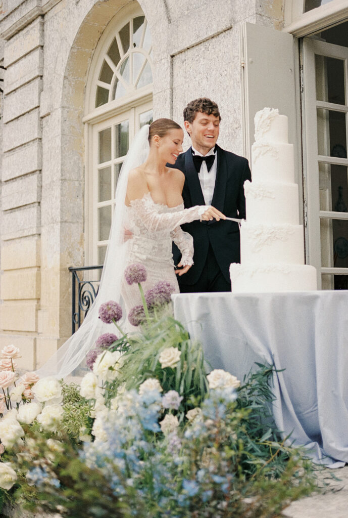 couple cutting cake in front of chateau d'hebertot