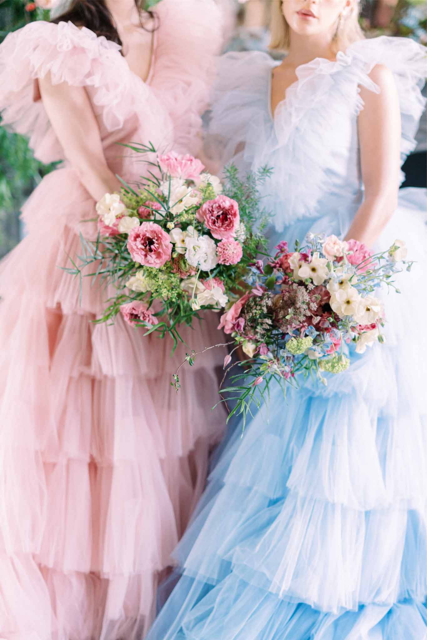 Three bridesmaids in blush, blue and white tulle dresses holding garden rose bouquets