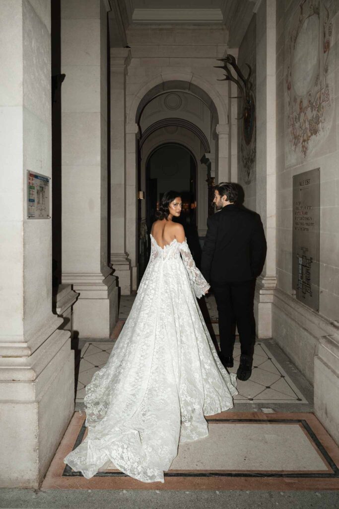 Chateau de Ferrieres Avecamour bride groom holding hands long lace dress trail vintage hallway