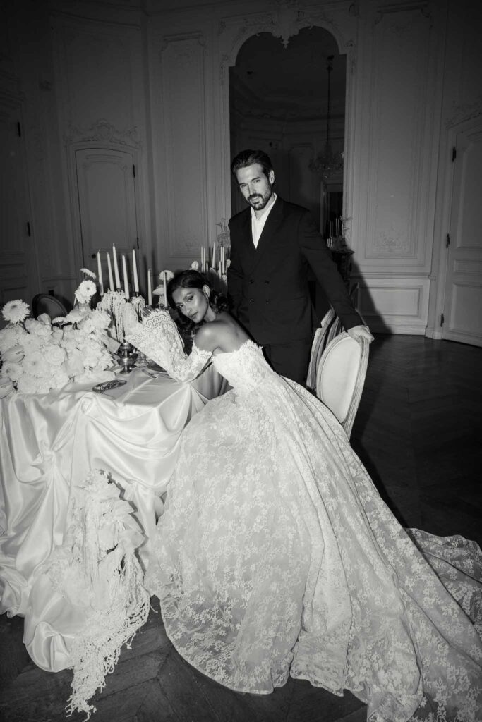 Chateau de Ferrieres Avecamour bride sitting groom standing reception table big lace ball gown long trail black white photo