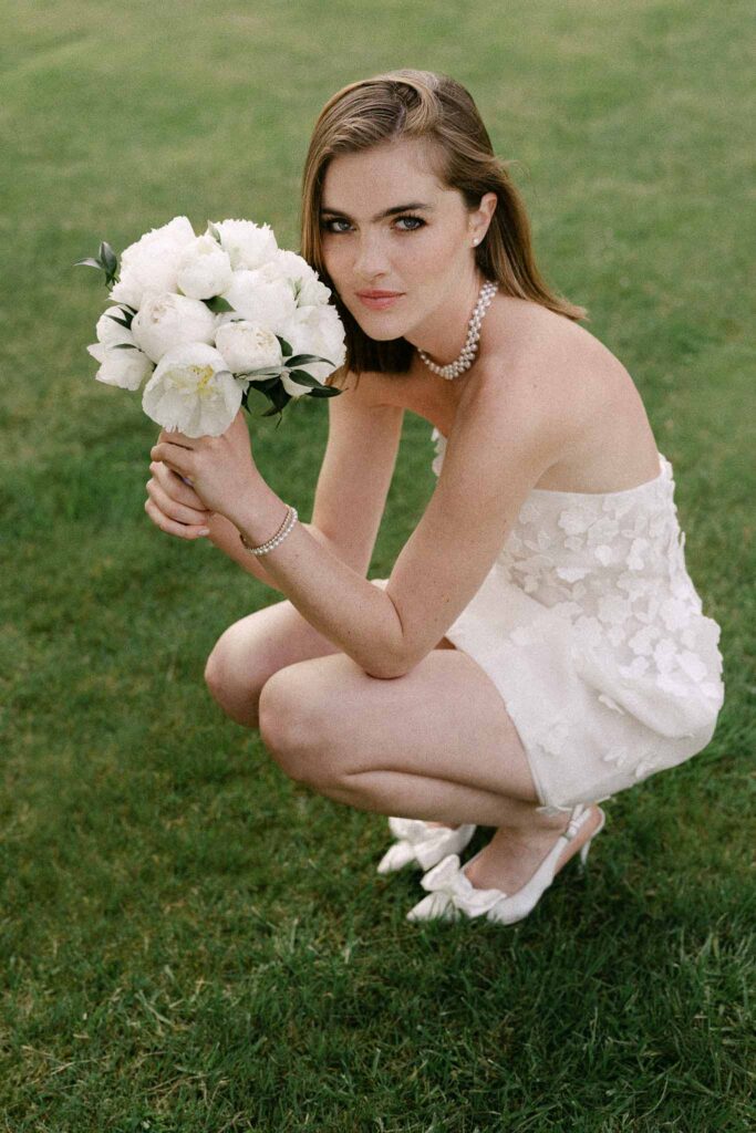 Chateau sainte claire keith flament bride holding bouquet sitting grass short dress diamond necklace